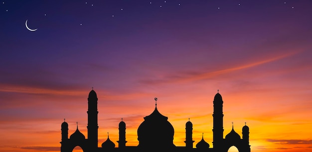 Panoramic view of silhouette mosque dome and crescent moon with stars in the evening twilight sky