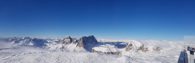 Panoramic view of snow covered landscape against clear blue sky