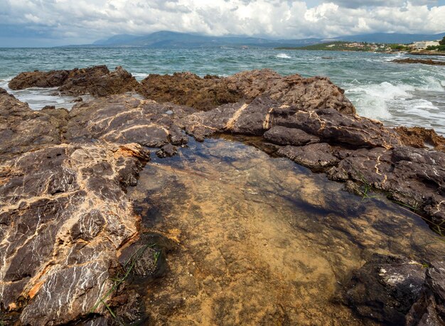 Panoramic view of the Stunning storm clouds waves and the rocky beach in the Aegean sea in Greece