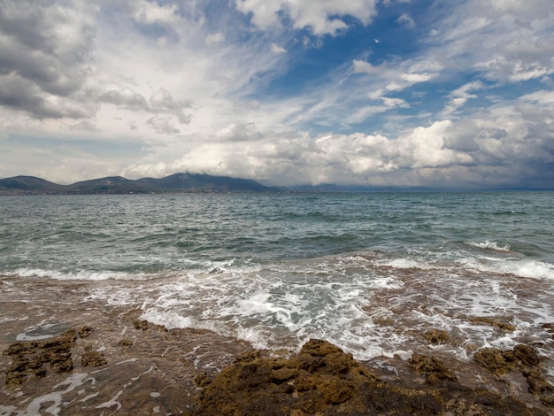 Panoramic view of the stunning storm clouds waves and the rocky\
beach in the aegean sea in greece