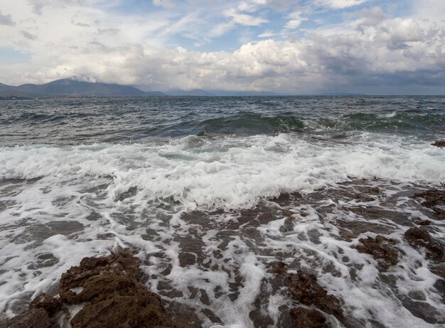 Panoramic view of the Stunning storm clouds waves and the rocky beach in the Aegean sea in Greece