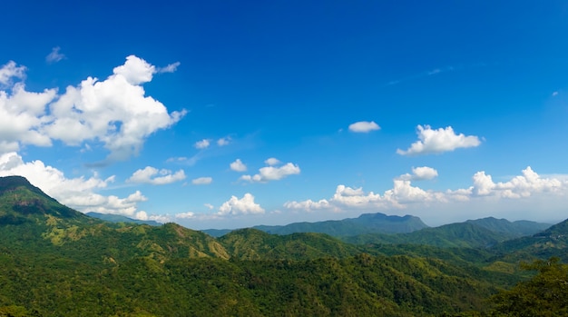 Panoramic view of summer green mountains, blue sky and white clouds.