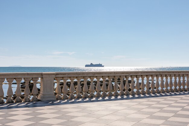 Panoramic view of Terrazza Mascagni (Mascagni terrace) in front of the Ligurian sea on the western coast of Tuscany in Livorno. People walk and rest on terrace