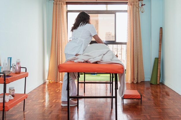 Photo panoramic view of a young girl massaging another girl lying on a therapy table in a home spa