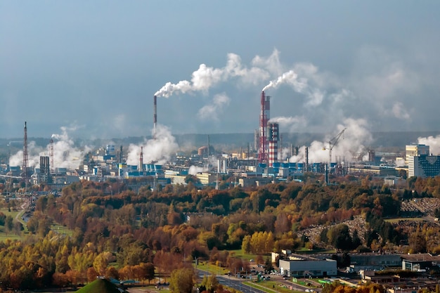 Panoramisch luchtfoto van de rook van pijpen als achtergrond van een enorm wooncomplex met hoogbouw en particuliere sector Lucht- en waterverontreinigingsconcept