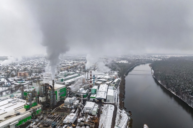 Panoramisch luchtfoto van de rook van pijpen als achtergrond van een enorm wooncomplex met hoogbouw en particuliere sector Lucht- en waterverontreinigingsconcept