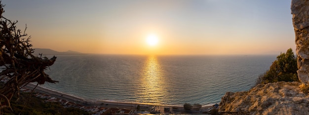 Panoramisch uitzicht op de middellandse zee vanaf het zandstrand met zonnestralen tegen de achtergrond van de zonsondergang