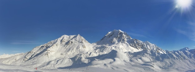 Panoramisch uitzicht op de piekberg bedekt met sneeuw onder de zonnige blauwe hemel