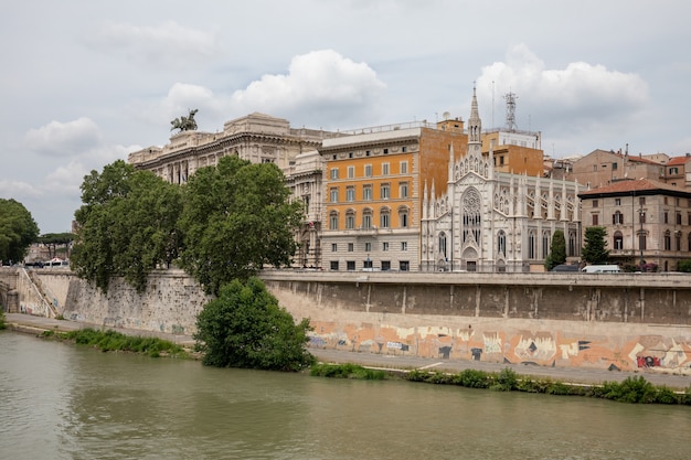 Panoramisch uitzicht over de stad rome met de rivier de tiber en de oude kerk aan de andere kust. zomerdag en dramatische blauwe lucht