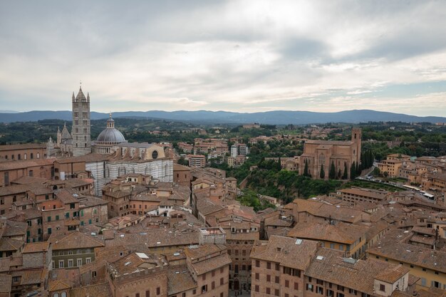 Panoramisch uitzicht over de stad Siena met historische gebouwen en verre groene velden van Torre del Mangia is een toren in de stad. Zomer zonnige dag en dramatische blauwe lucht