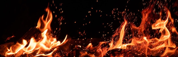 Panoramisch zicht op brandende vlam en vonken op zwart