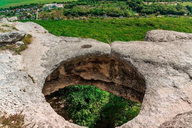 Foto panoramisch zicht op een enorm gat in de grond tussen groen veld en berg op zonnige zomerdag op de krim