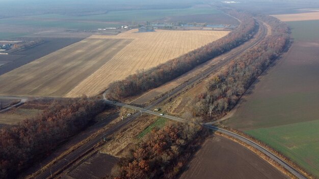 Panoramisch zicht op spoorwegovergang tussen bomenvelden herfstdag luchtdrone