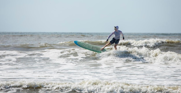 Panoramisch zicht van een man van middelbare leeftijd die surft in de Atlantische Oceaan