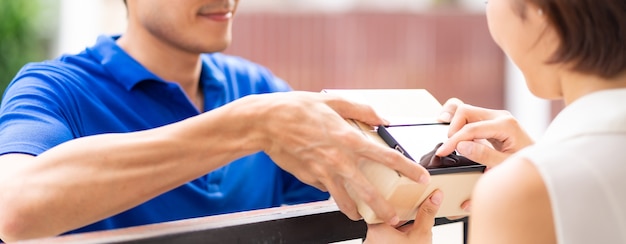 Panoramische Aziatische vrouw ondertekent elektronische handtekening naar draagbaar mobiel apparaat na ontvangstpakket