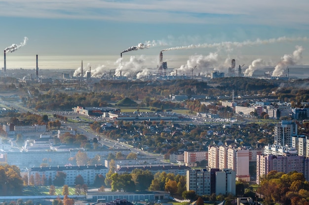 Panoramische luchtfoto van de rook van pijpen als achtergrond van een enorm wooncomplex met hoogbouw en particuliere sector Lucht- en waterverontreinigingsconcept