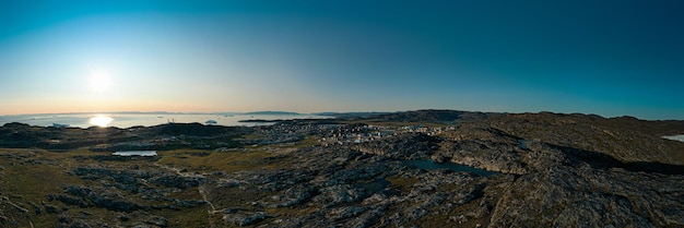 Panoramische opname van een droog rotsachtig natuurlijk landschap met uitzicht op zee tijdens zonsondergang in de Groenlandse ijsbergen