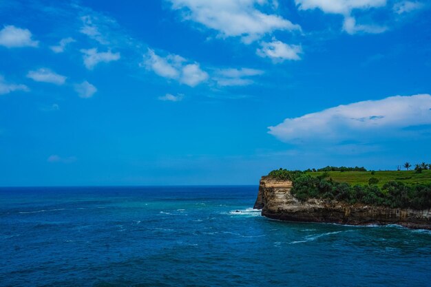 Pantai Klayar or Klayar Beach with rocks and strong waves against the blue sky