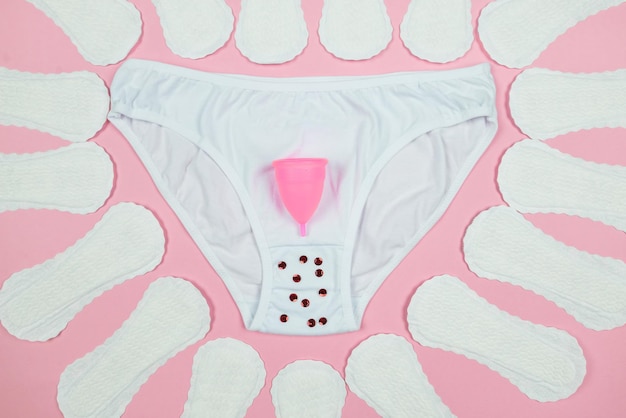 Panties pads menstrual cup on a pink background The concept of women's periods