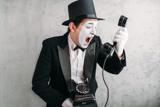 Foto pantomime-acteur die met retro telefoon presteert