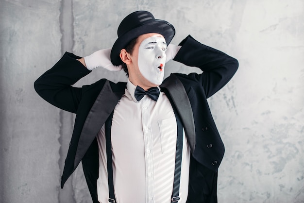 Pantomime artist with makeup mask. Mime in suit, gloves and hat.