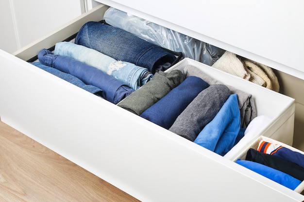 Pants folded according to the method of Marie Kondo. Vertical storage of clothes in a chest of drawers. Storage organization. Order and cleanliness. Quarantine, self-isolation, housework. Accuracy.