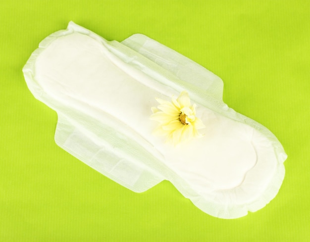 Photo panty liner and yellow flower on green background closeup