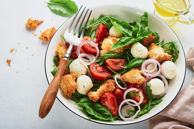 Panzanella broodsalade traditioneel eten van Italië met tomaten mozzarella ballen basilicum ui en brood op lichtgrijze achtergrond traditionele Italiaanse keuken bovenaanzicht kopie ruimte