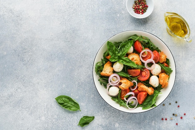 Panzanella Italiaanse broodsalade Traditioneel eten van Italië met tomaten mozzarella ballen basilicum ui en brood op lichtgrijze achtergrond Traditionele Italiaanse keuken bovenaanzicht kopie ruimte