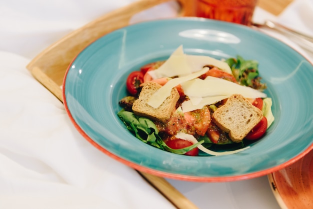 Panzanella met croutons en kaas op een blauw bord op een dienblad als maaltijd in bed