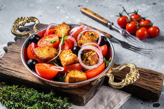 Panzanella traditionele italiaanse salade met tomaten, ui en broodcroutons. grijze achtergrond. bovenaanzicht.