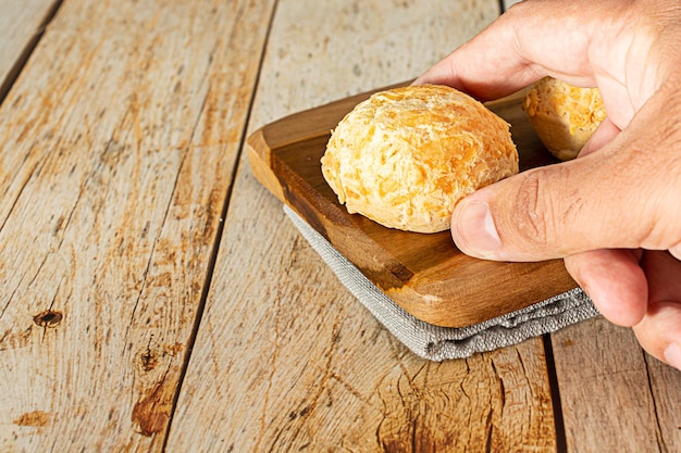 pão de queijo over wooden table, male hand picking up