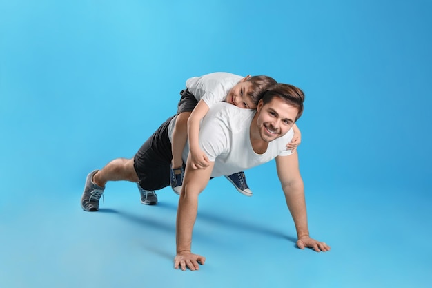 Papa doet push-ups met zoon op zijn rug tegen gekleurde achtergrond
