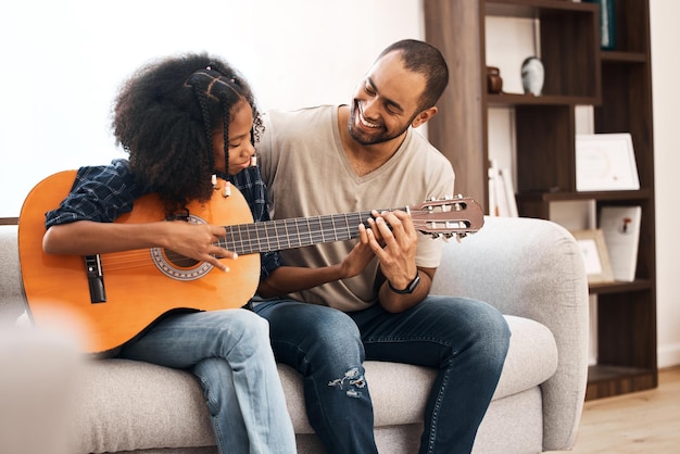 Papa elke dochters nummer één fan Shot van een jong meisje dat thuis gitaar leert spelen met haar vader