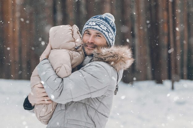 Papa en baby wandelen door het bos Papa houdt een baby in zijn armen in de winter Papa en dochter buiten in de winter