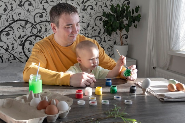 Papa en kind schilderen eieren voor Pasen