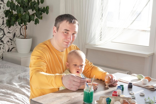 Papa en kind schilderen eieren voor Pasen