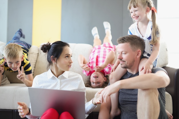 Papa en mama praten met elkaar en kinderen spelen op laptop naast hen