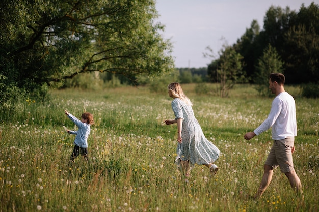 Papa en mama rennen achter baby aan over het veld, jongen speelt en rent van ze weg. Adoptie concept foto