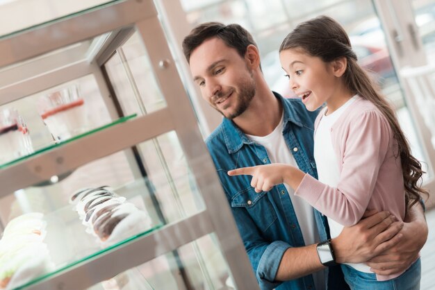 Papa en meisje kiezen voor lekkere snoepjes in café.