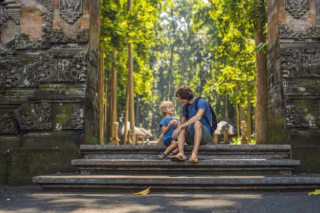 Papa en zoonsreizigers die het bos van Ubud ontdekken in Monkey forest, Bali, Indonesië. Reizen met kinderen concept.