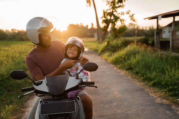 Papa helpt haar dochter met het vastmaken van de helm