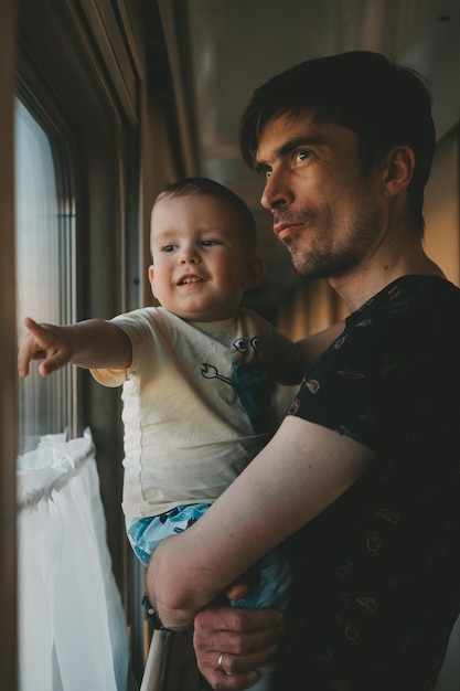 papa houdt de baby in zijn armen in de treinwagon en ze kijken samen uit het raam