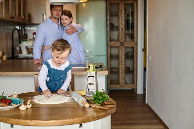 Papa mama en hun dochter koken samen pizza in de keuken T