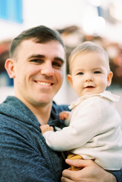 Papa met een baby in zijn armen staat in de buurt van het huis Portret