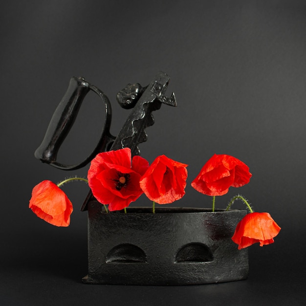 사진 1920년대 목탄 철제 상자가 있는 양귀비꽃 붉은 양귀비는 복고풍 검정색 배경에 피어 신선한 자연을 배경으로 골동품