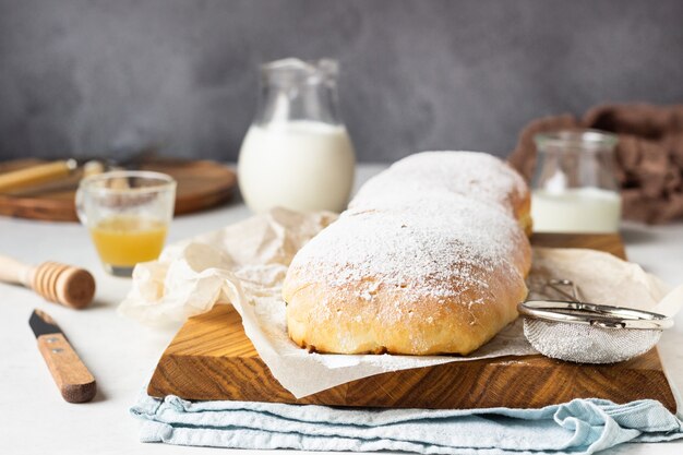 Papaverzaadbroodje of strudel op houten raad die met poedersuiker wordt bestrooid.