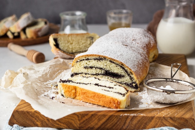 Papaverzaadbroodje of strudel op houten raad die met poedersuiker wordt bestrooid.