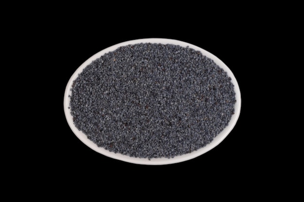 Papaverzaden in een kleine witte ovale keramische kom geïsoleerd op een zwarte achtergrond bovenaanzicht