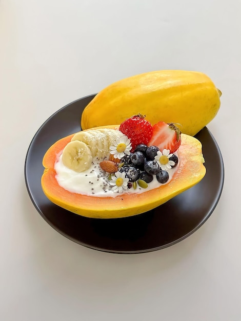 A papaya bowl with fruit and yogurt on it.